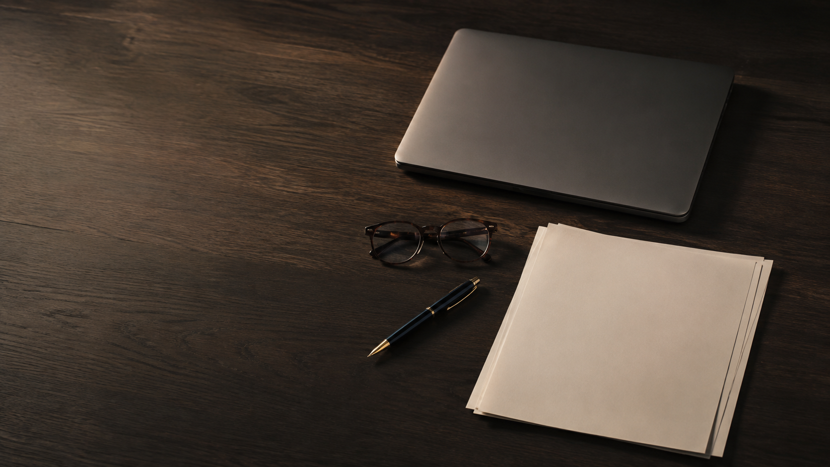 Legal documents, laptop, reading glasses and fountain pen on a dark wooden desk